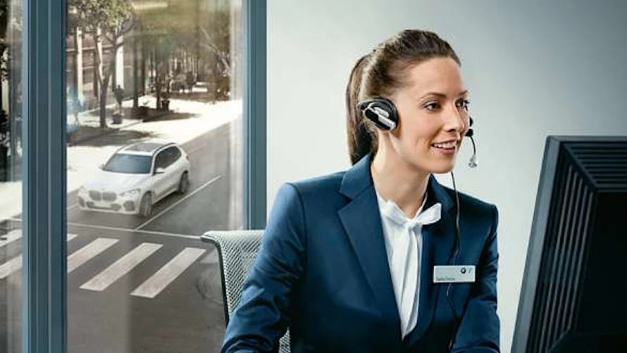 BMW Kundenservice Ansprechpartnerin mit Headset und freundlichem Lächeln.